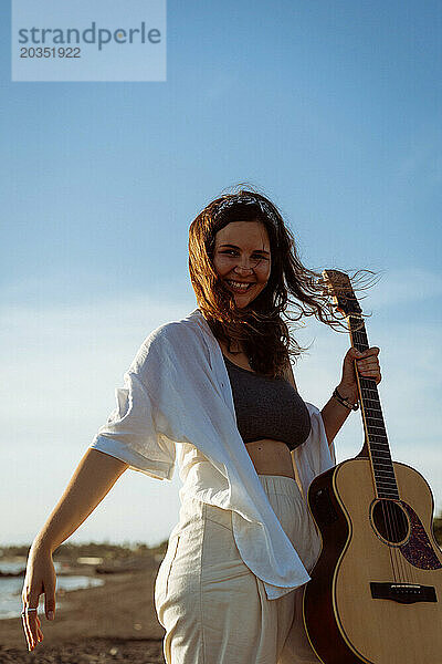 Musikerin singt und spielt Gitarre am Strand. In einem Bandana. Bali