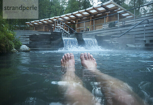 Nackte Beine eines Mannes  der sich in Laird Hot Spring  British Columbia  Kanada  entspannt