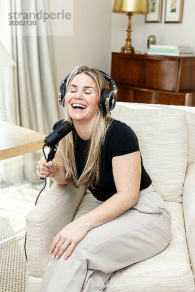 Strahlende Frau  die beim Podcasting zu Hause lacht