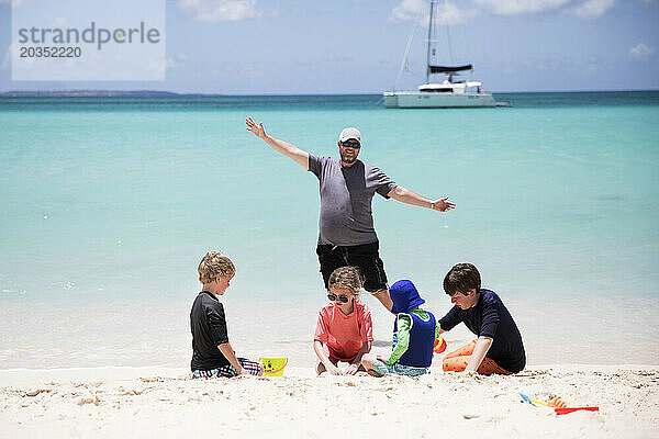 Dummer Vater steht hinter vier Kindern am karibischen Strand