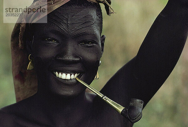 Eine Frau raucht eine Pfeife mit Narben  die sie mit ihrem Stamm  dem Sudan  identifizieren.