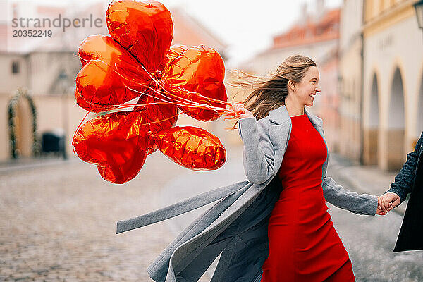 Junges Paar geht mit Luftballons im Herzen durch Prag