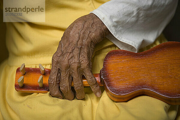 Eine ältere Frau hält eine Spielzeuggitarre im Seniorenheim Unserer Lieben Frau von Guadalupe in Mexiko-Stadt