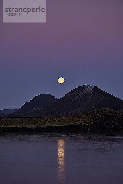 Mond über Bergen und ruhiger See in der Nacht