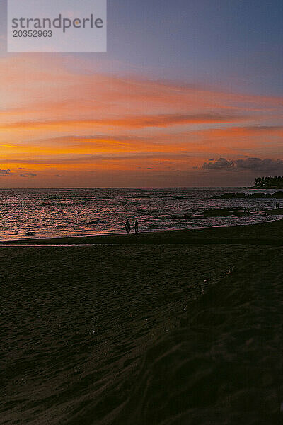 Menschen bei Sonnenuntergang am Strand am Meer.