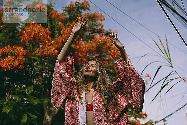 Junge Frau mit langen Haaren im Kimono geht auf Bali die Straße entlang.