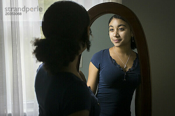 Ein gemischtrassiges Teenager-Mädchen schaut sich im Spiegel an