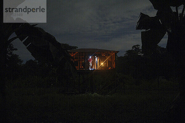 Zwei Menschen tragen nachts in einer Hütte im Dschungel von Nicaragua Stirnlampen.