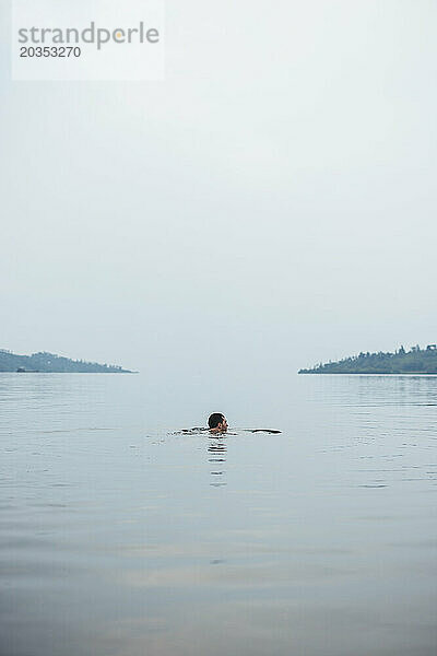 Mann schwimmt in friedlichen Gewässern des Kivu-Sees  Ruanda