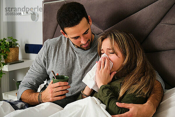 Ehemann kümmert sich um seine Frau  weil sie im Bett an Grippe erkrankt ist.