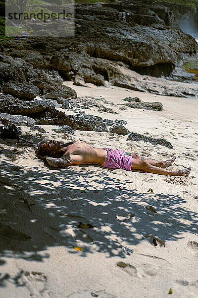 Mann mit Tätowierungen entspannt sich im Urlaub am Sandstrand. Bali