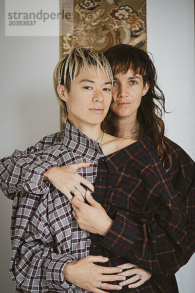 Porträt eines queeren weiblichen Ehepaares  das zusammen ein Hemd trägt