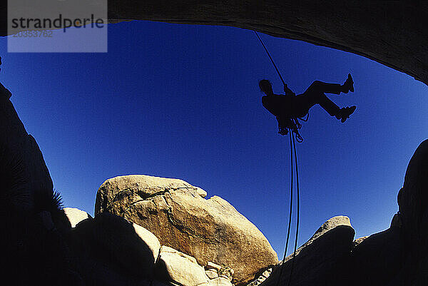 Kletterer beim Abseilen einer Felswand  Joshua Tree National Park  Kalifornien (Silhouette  Weitwinkel).