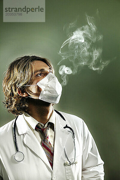 Ein als Arzt verkleideter Mann mit Maske atmet Rauch aus  nachdem er medizinisches Marihuana geraucht hat.