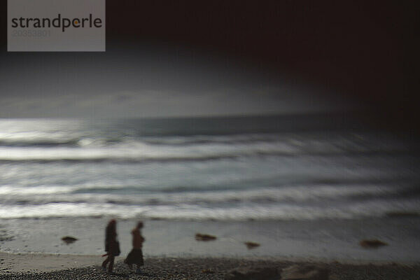Zwei Menschen gehen an einem dunklen Strand in Encinitas  Kalifornien  entlang