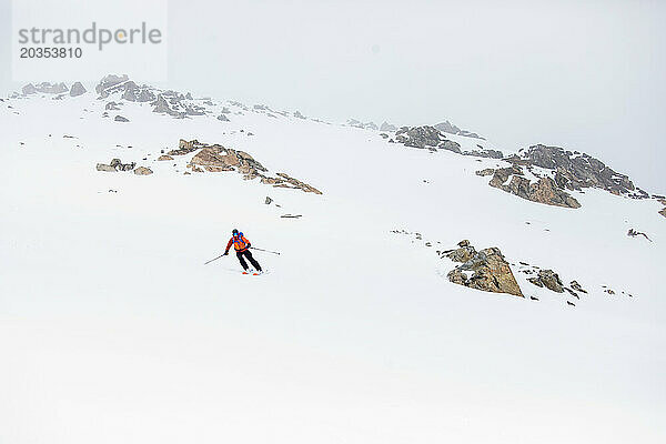 Fernsicht auf Backcountry-Skifahrer unterhalb eines Felsvorsprungs