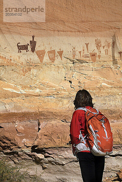 Frau wandert in Richtung einer großen Piktogrammtafel  Horshoe Canyon  Utah. Frau wandert in Richtung einer Piktogrammtafel  Horshoe Canyon Canyonlan