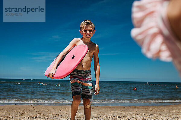 Lächelndes Kind am Strand des Michigansees mit Boogie-Board