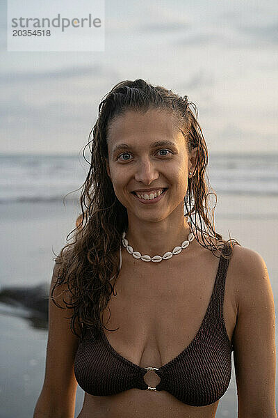 Porträt einer fröhlichen jungen Frau mit glücklichem lockigem Haar  die auf dem Meer läuft. Bali