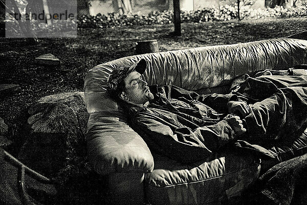 Ein obdachloser junger Erwachsener schläft auf einer ausrangierten Couch im Universitätsviertel von Seattle.