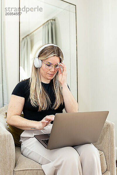 Eine Frau arbeitet zu Hause konzentriert mit Kopfhörern an ihrem Laptop