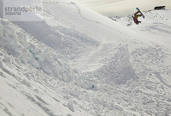 Ein Snowboarder macht einen Sprung und macht einen Backflip am Cerro Catedral in Argentinien