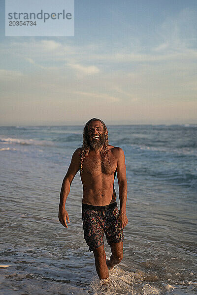 Ein arabischer Mann mit langen lockigen Haaren schwimmt im Meer.