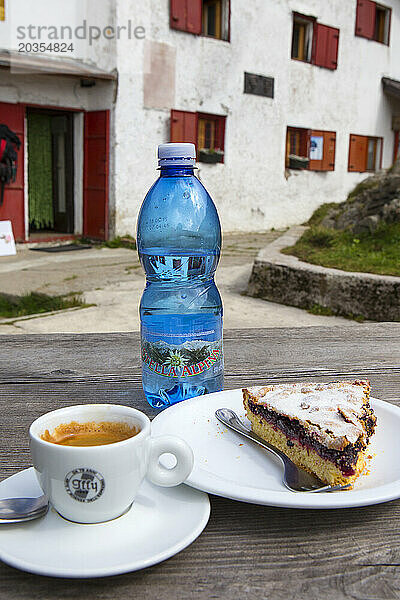 Eine Rast auf einer italienischen Berghütte wird mit frisch gebrühtem Espressokaffee  lokalem Mineralwasser und einem hausgemachten Kuchen gefeiert.