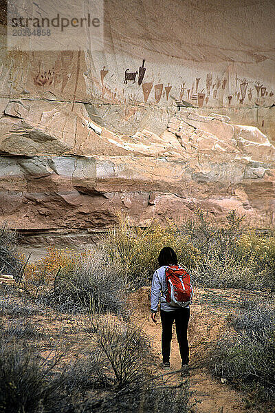 Frau wandert in Richtung einer großen Piktogrammtafel  Horshoe Canyon  Utah. Frau wandert in Richtung einer Piktogrammtafel  Horshoe Canyon Canyonland