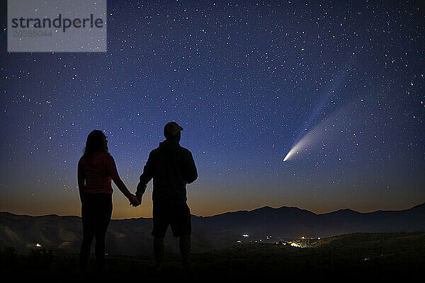 Ein Mann und eine Frau stehen voller Ehrfurcht da  während sie den prächtigen Kometen betrachten