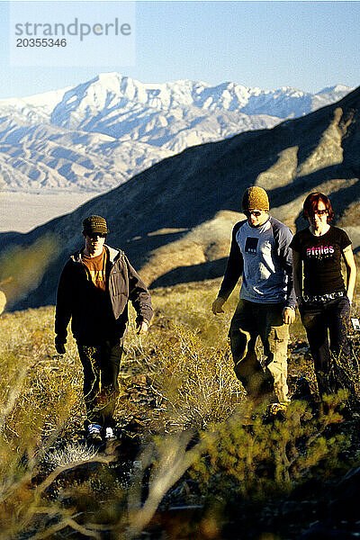 Drei Menschen gehen bei Sonnenuntergang in der Wüste spazieren  Death Valley  Kalifornien.