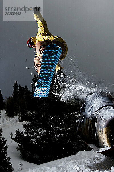 Junger Erwachsener beim Snowboarden von einem Metallrohr in Colorado.