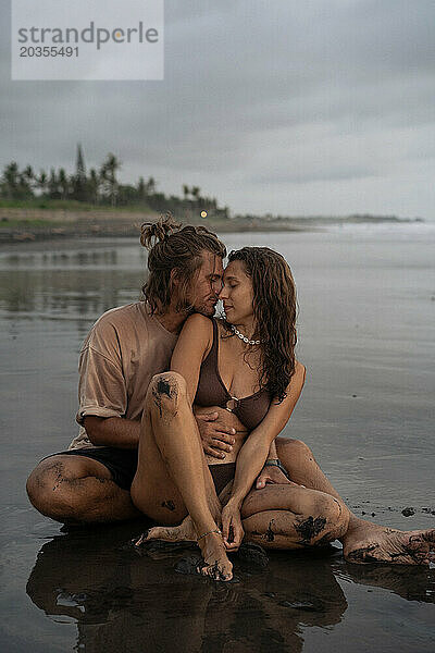 Junges fröhliches  glückliches verliebtes Paar  das sich am Strand küsst.