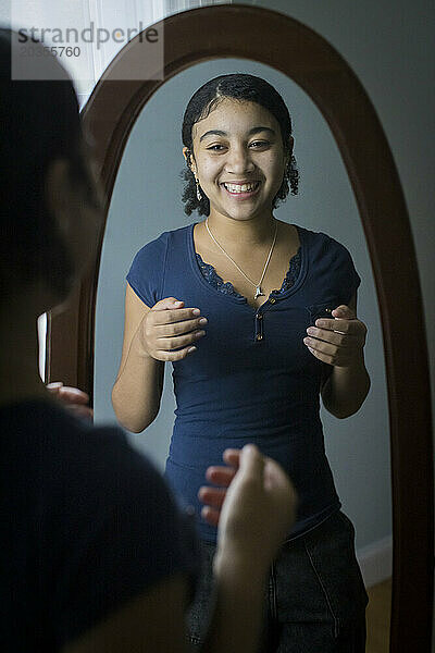 Gemischtes Teenager-Mädchen lacht im Spiegel über sich selbst