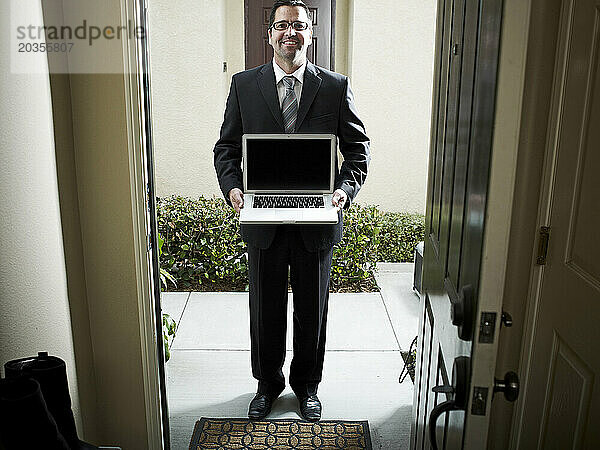 Geschäftsmann an der Tür  der einen Laptop-Computer hält.