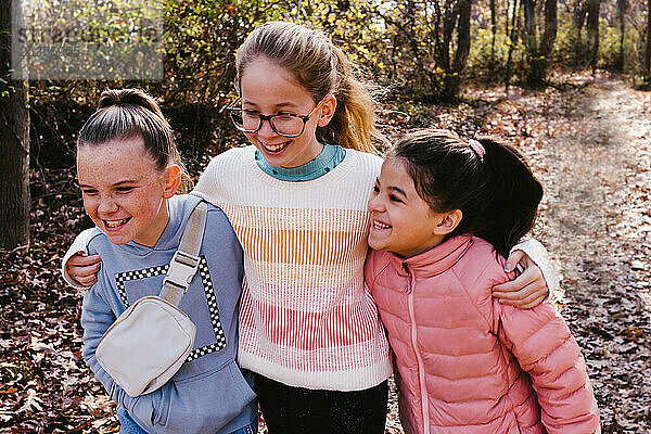 Girl cousins laugh and talk together while hiking in forest