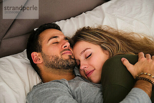 Spanisches verliebtes Paar  das umarmt auf einem Bett schläft.