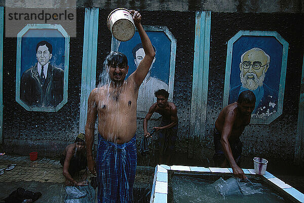 In Wohngebieten in Süd-/Zentral-Kalkutta  Indien  besuchen Männer Röhrenbrunnen zum Baden  Waschen von Kleidung und zum Auffüllen von Wasser für Trink-/Haushaltszwecke.