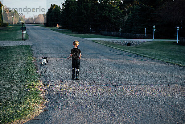 Weite Sicht auf Junge und Katze  die auf der ländlichen Nachbarschaftsstraße spazieren gehen