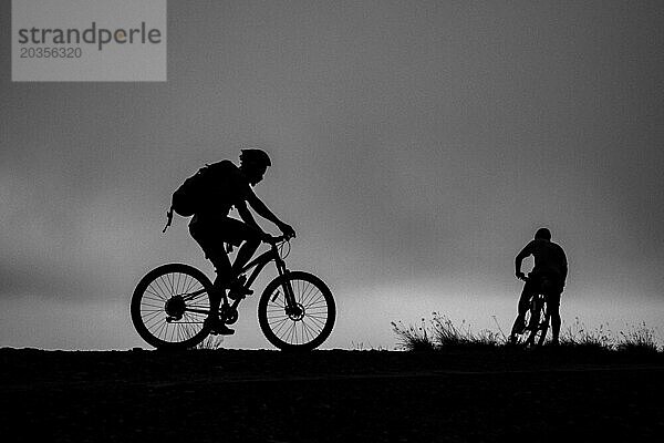 Zwei Radfahrer zeichnen sich als Silhouette gegen den Himmel ab  Ruanda