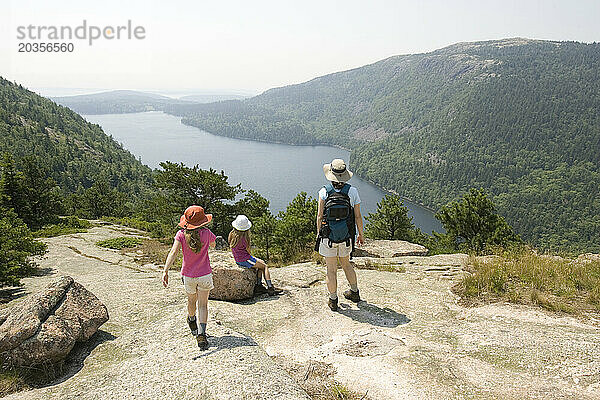 Drei Personen betrachten die Aussicht vom Gipfel des Bubble Mountain im Acadia-Nationalpark in Maine.