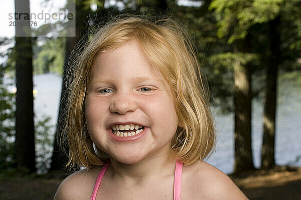 Ein junges rothaariges Mädchen  3-5 Jahre alt  posiert für ein Porträt im Freien.