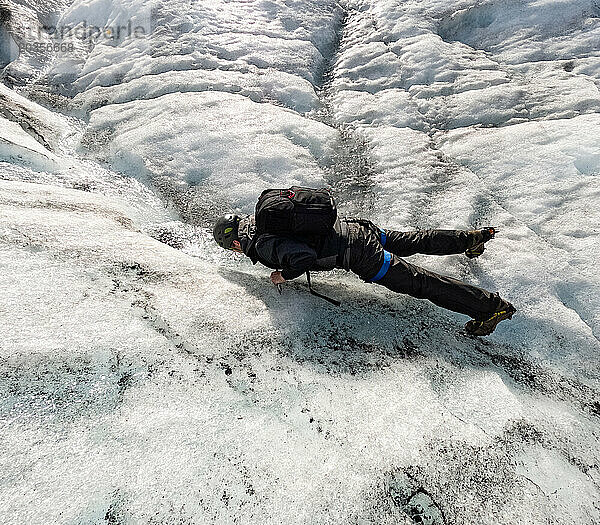 Mann drängt sich auf einer Wanderung hoch  um Gletscherwasser auf dem Gletscher zu trinken