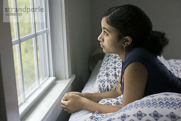 Biraciales Teenager-Mädchen schaut deprimiert aus dem Fenster