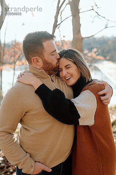 Paar umarmt sich lächelnd und lachend auf einem Pfad im Wald