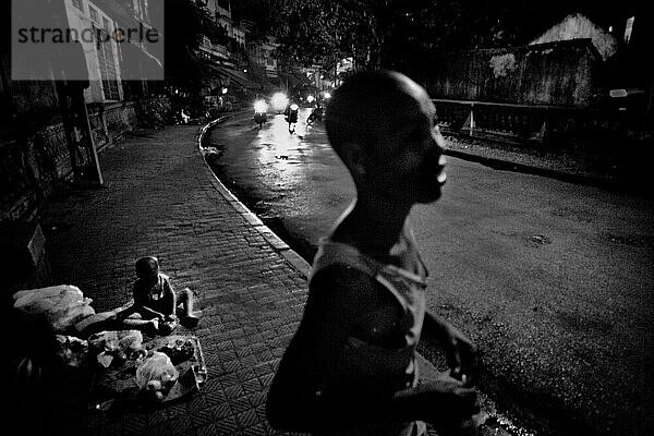 Mutter steht auf der Straße und wartet auf einen Freund  während ihr Sohn sitzt  Hanoi  Vietnam.