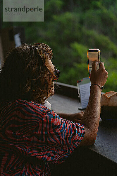 Ein Mann macht mit seinem Handy ein Foto des Sonnenuntergangs.