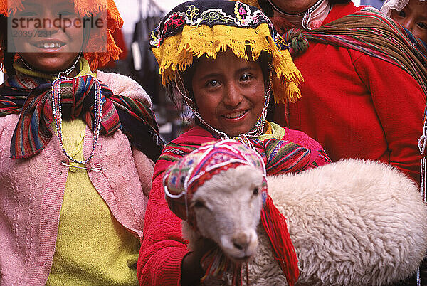 Junge Mädchen zeigen ein Lamm auf dem Pisac-Markt  Peru.