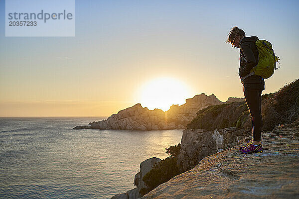 Blick auf eine Frau  die auf einer Klippe am Meer steht  Sardinien  Italien