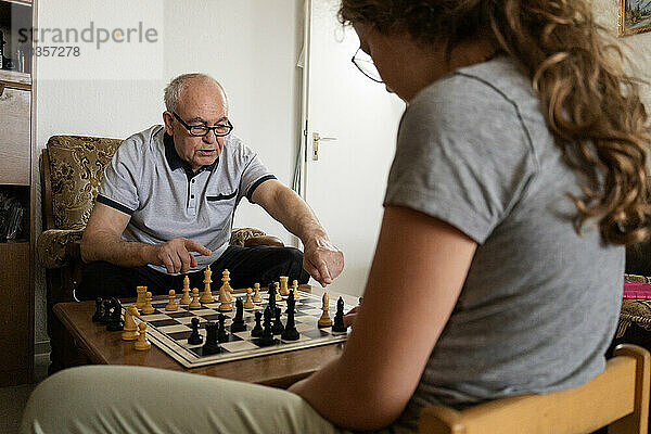 Großvater und Enkelin spielen Schach. Besuch der Enkelkinder